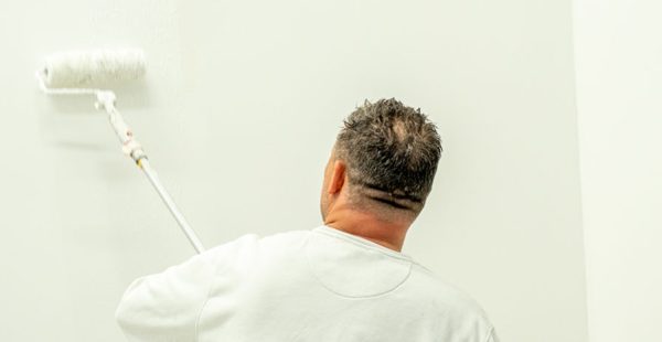 Maler streicht oberen Wand- oder Deckenbereich im Innenraum – Maler Quantius